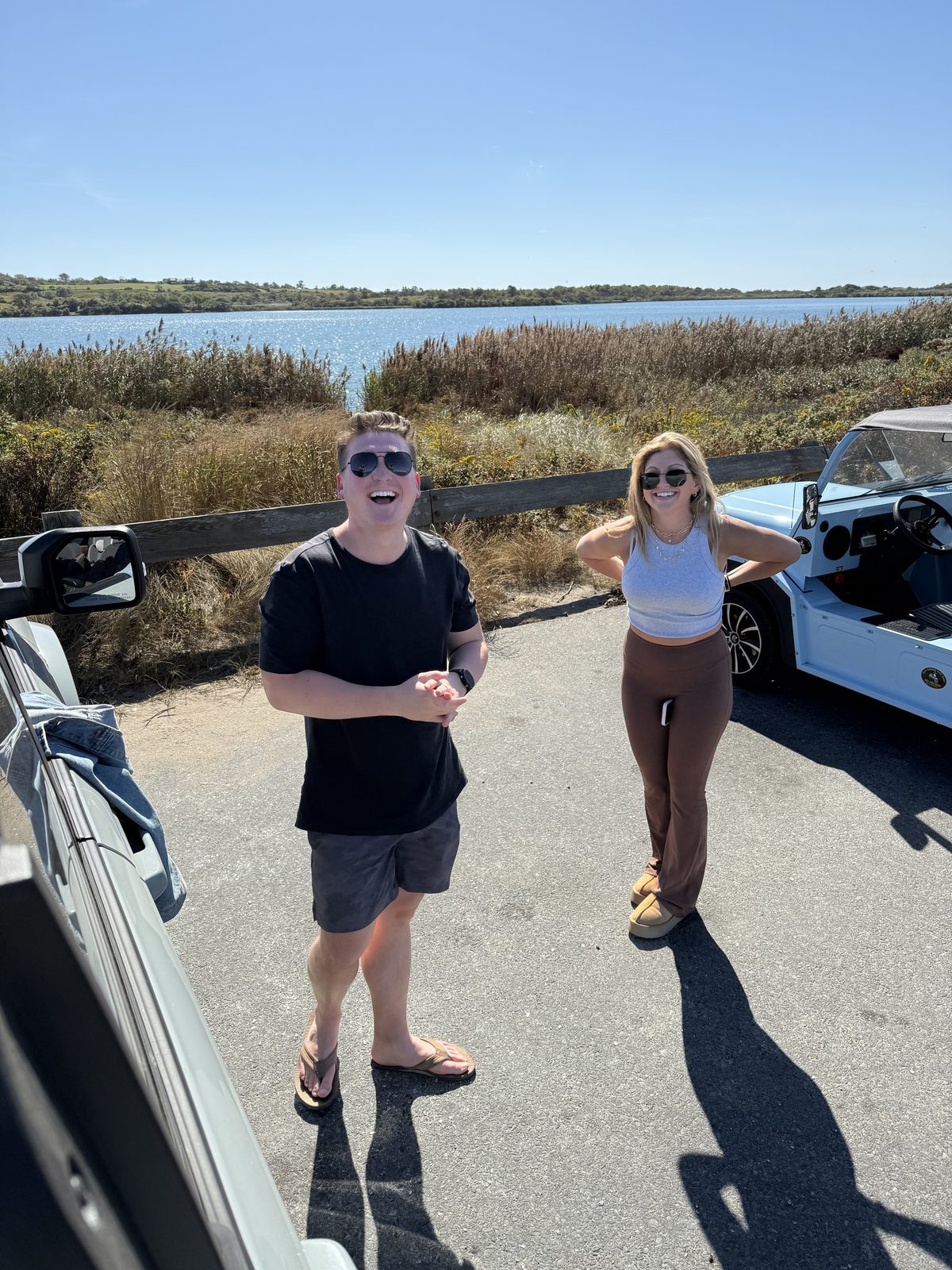 Laughing beside a light blue mini beach cruiser at a coastal pond