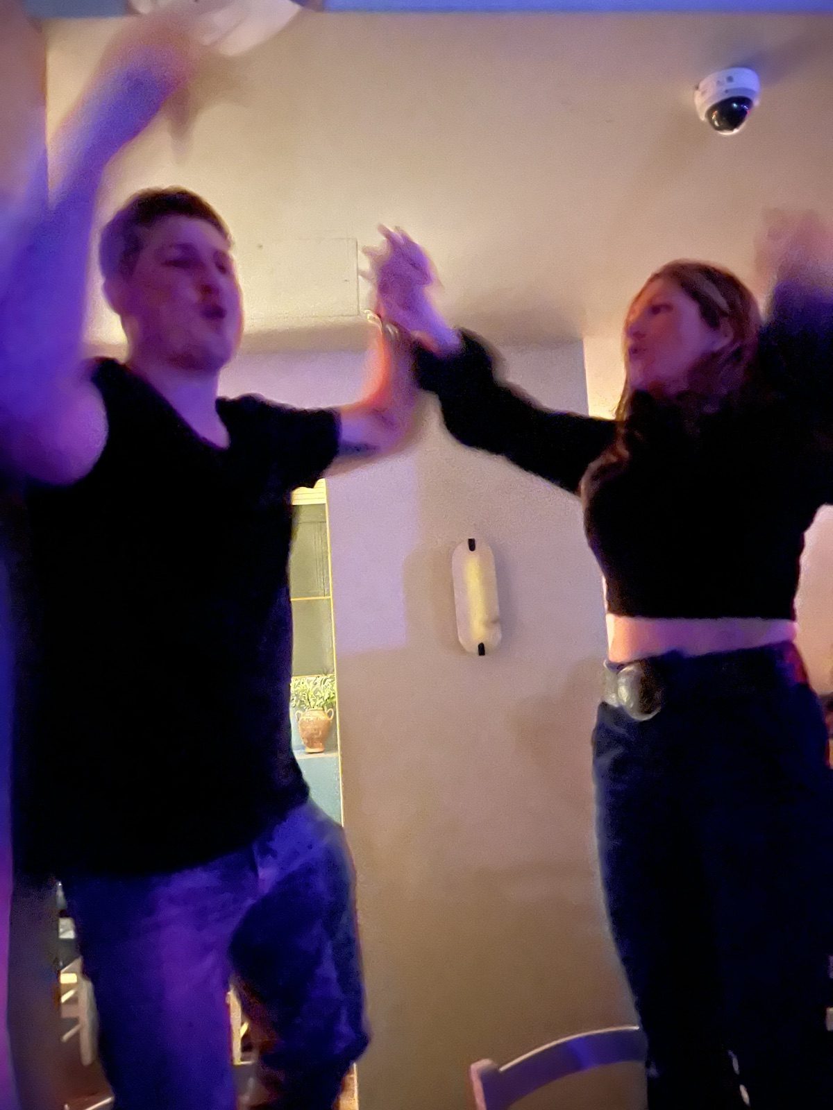 Andrew and Jenna mid high-five on a dance floor, motion-blurred and laughing