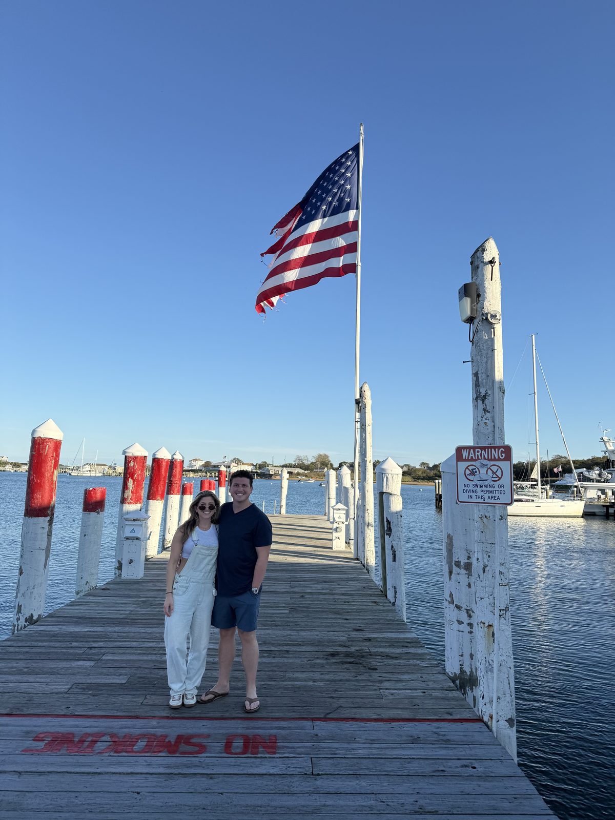 On a wooden dock beneath a big American flag