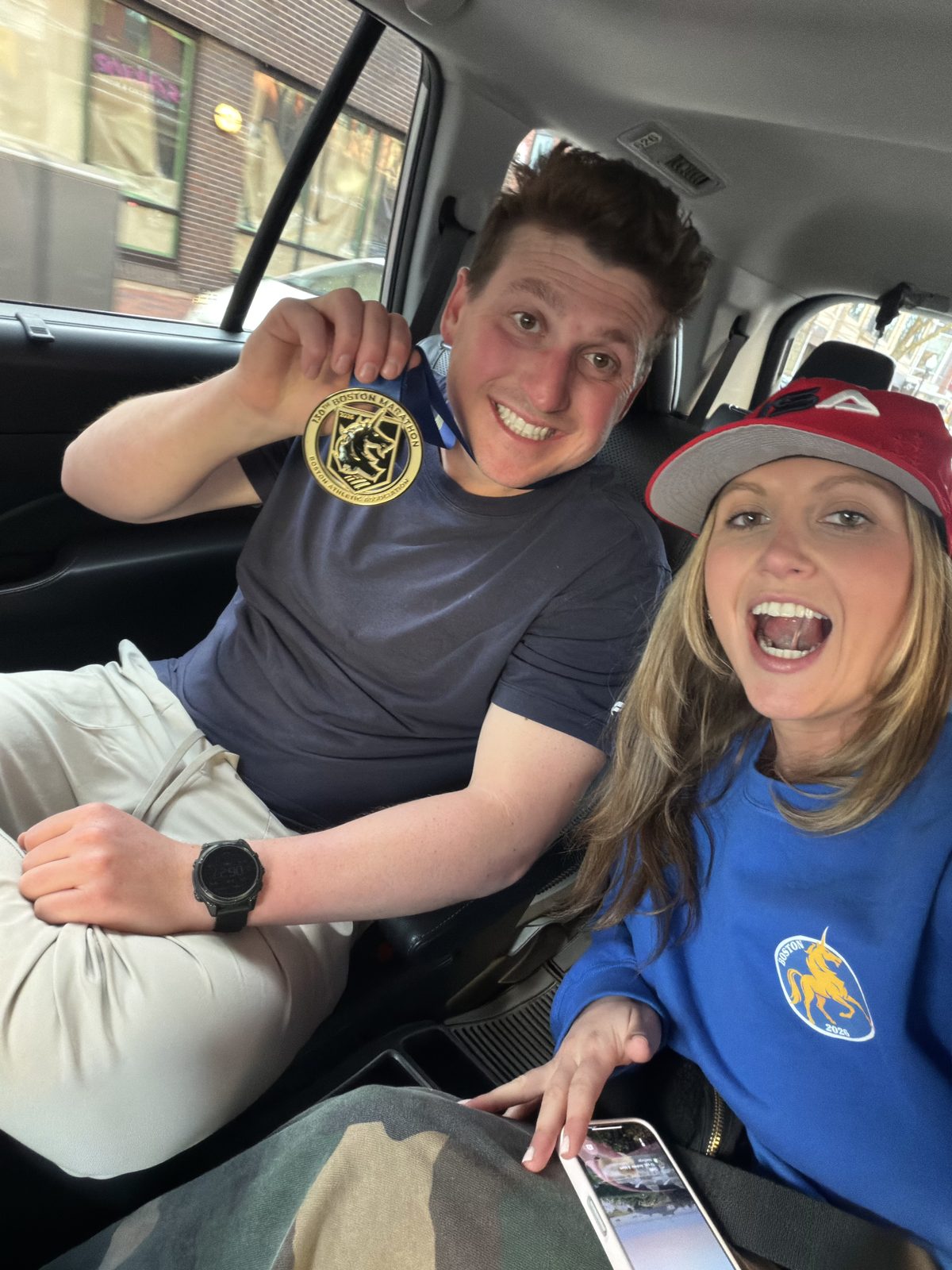 Holding up the Boston Marathon medal in the car after the race