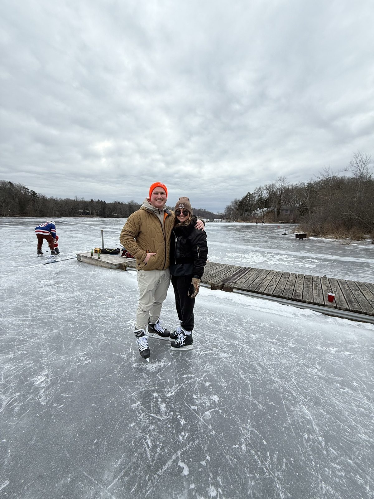 Andrew and Jenna in skates posing together on a frozen lake