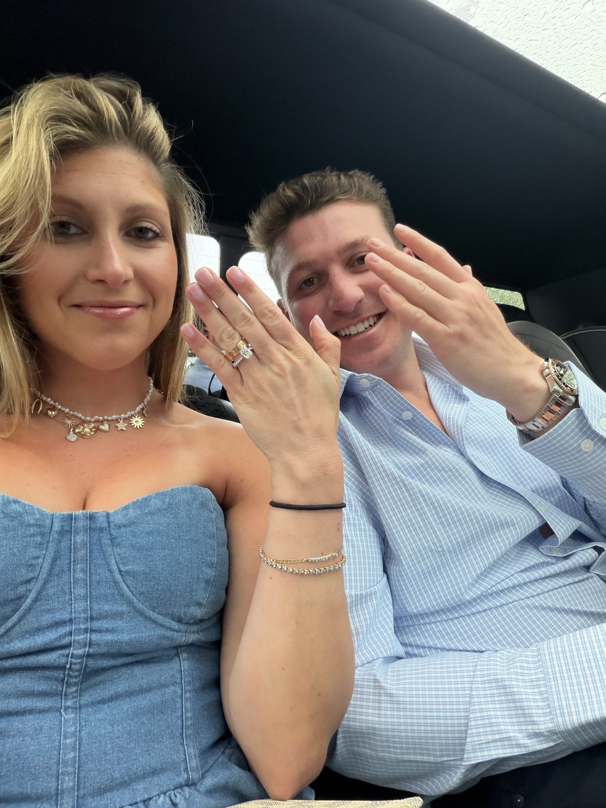 Car selfie of Jenna showing off her engagement ring while Andrew holds up his hand too