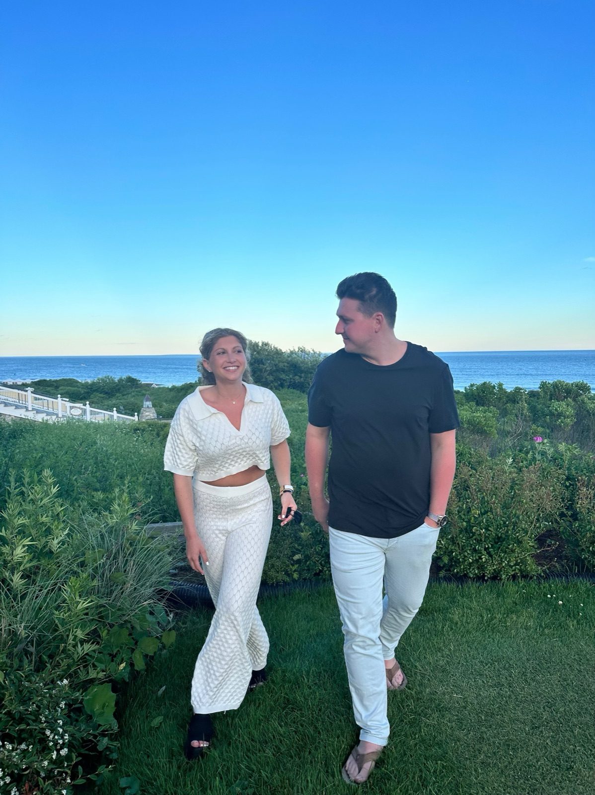 Andrew and Jenna walking on an oceanfront lawn at dusk