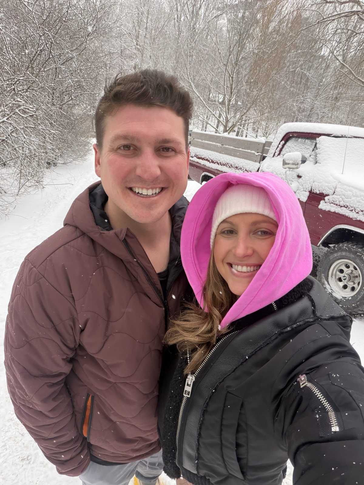 Selfie of Andrew and Jenna in the falling snow beside a snow-covered vintage truck